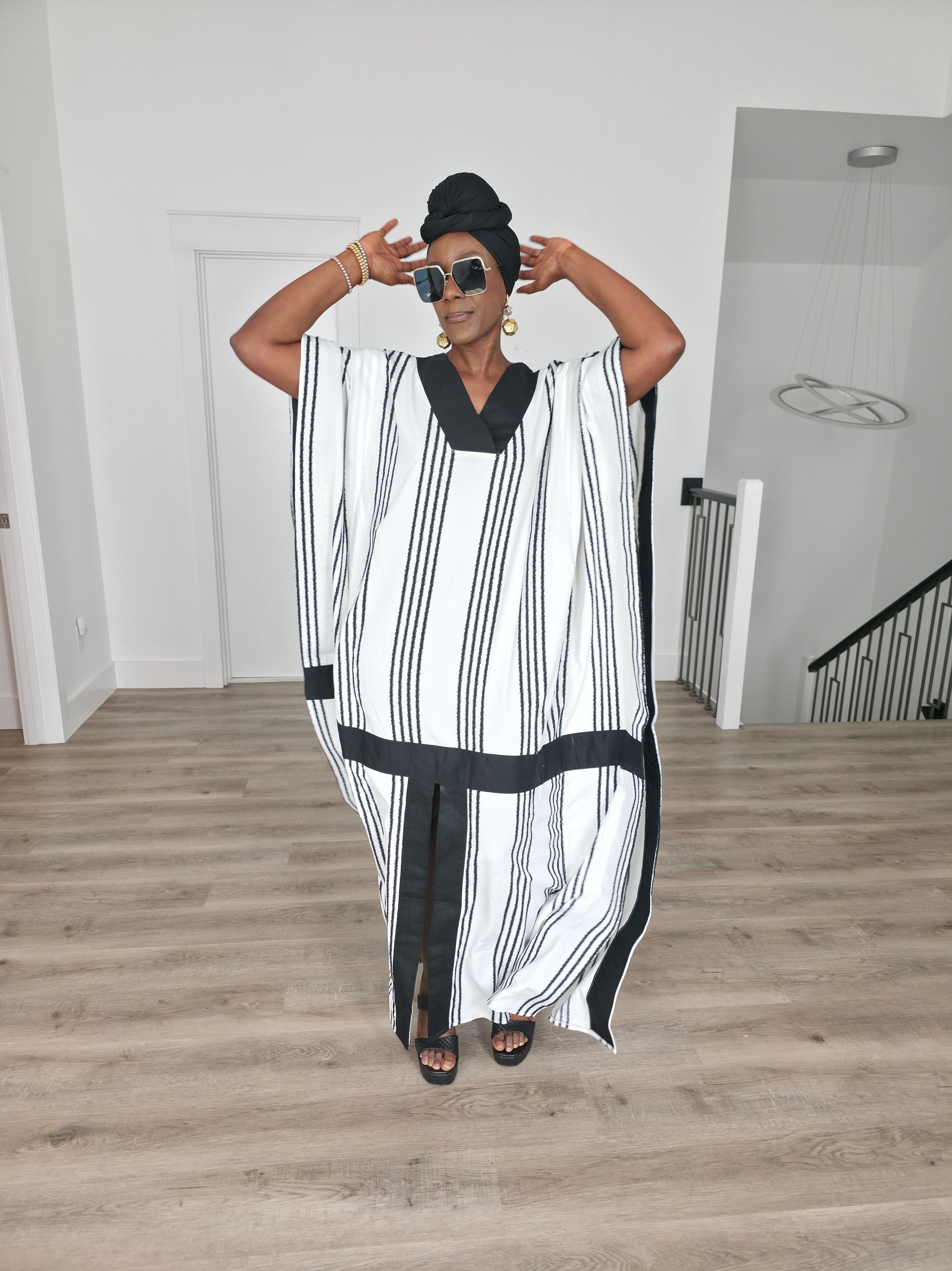 Obsidian Grid Boubou Kaftan featuring a black and white vertical stripe pattern with bold black structural borders and a matching black headwrap. Women's Wear