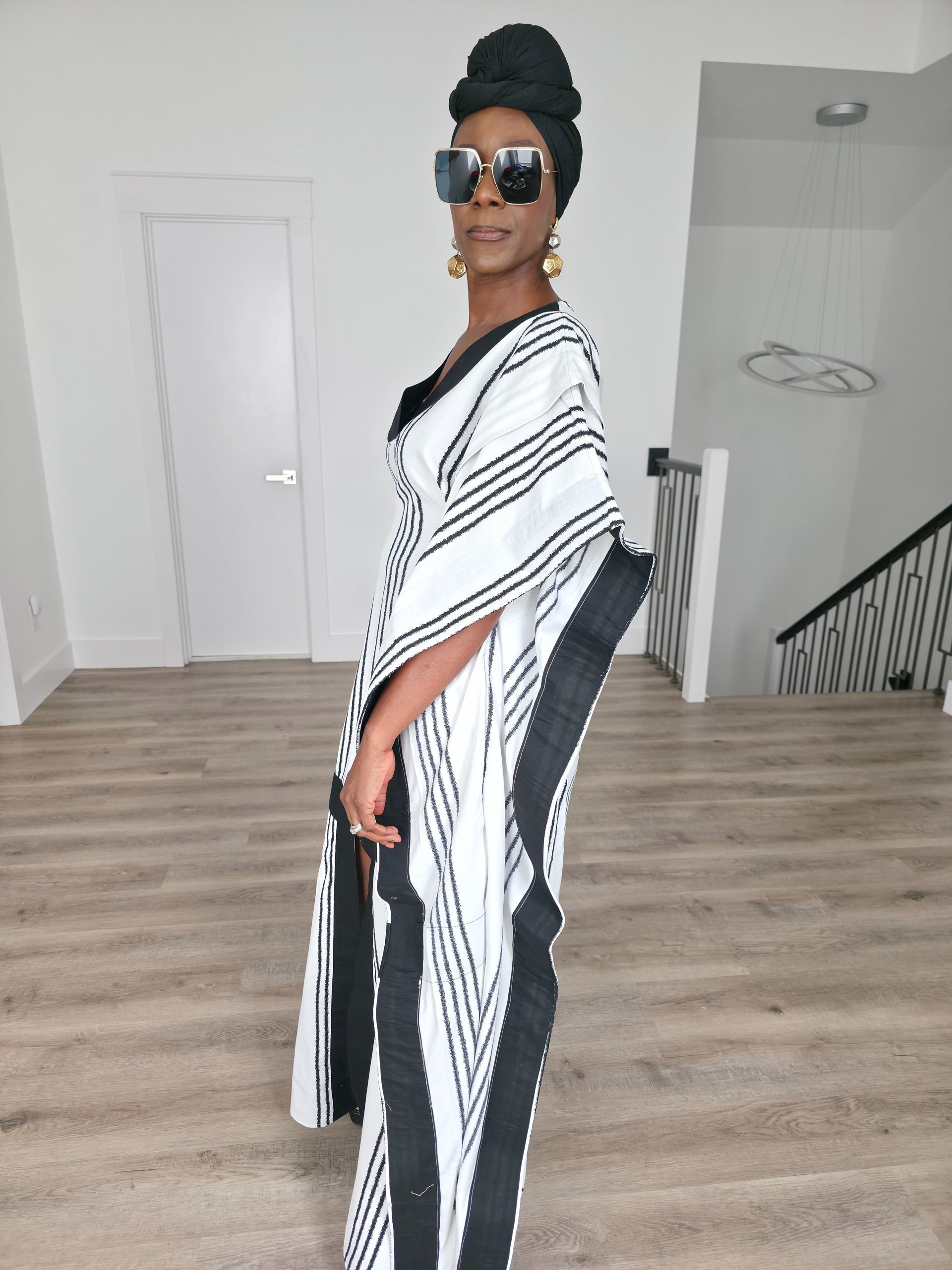 Obsidian Grid Boubou Kaftan featuring a black and white vertical stripe pattern with bold black structural borders and a matching black headwrap. Side View