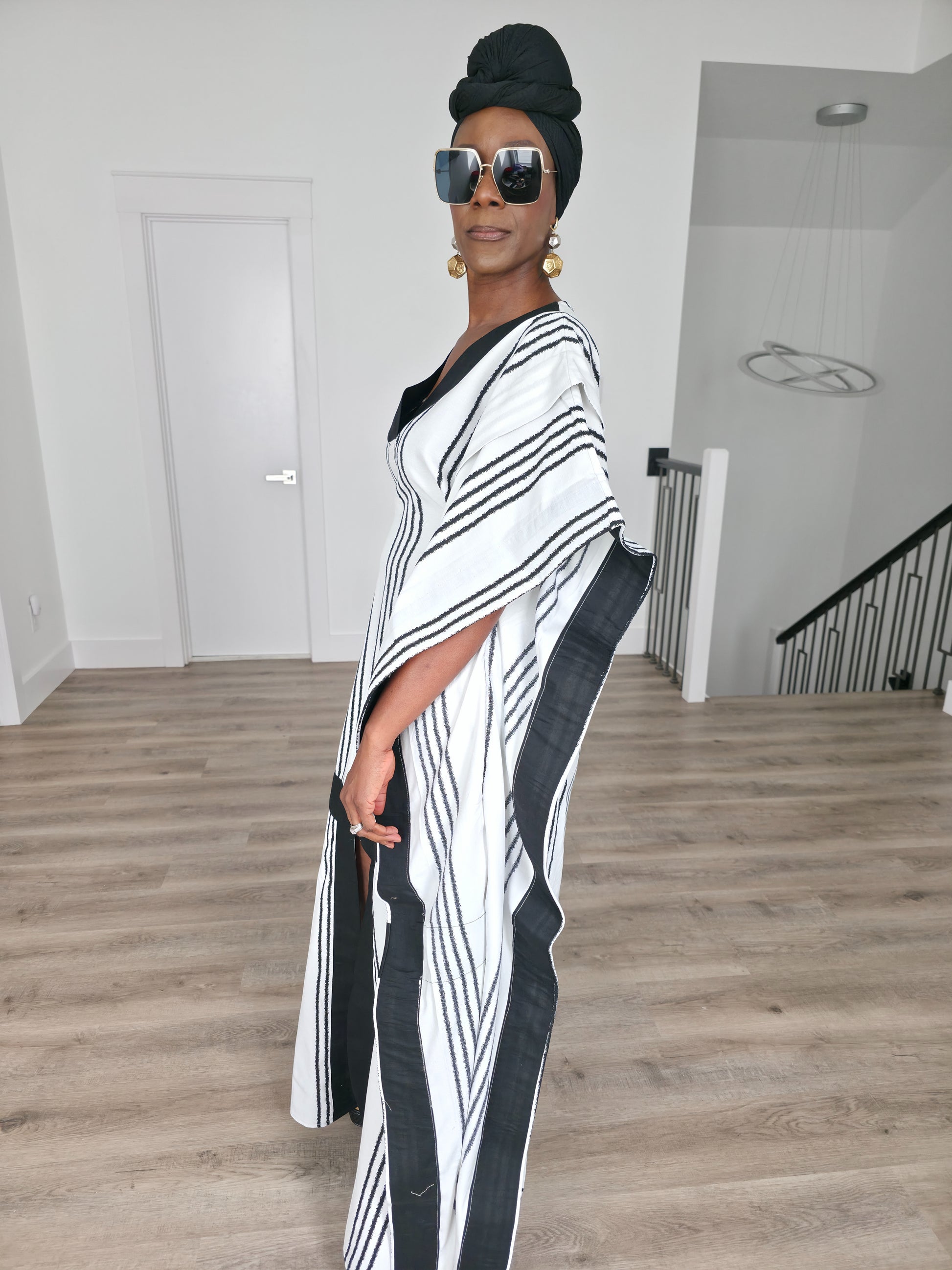 Obsidian Grid Boubou Kaftan featuring a black and white vertical stripe pattern with bold black structural borders and a matching black headwrap. Side View