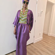 Luxury purple Boubou Kaftan featuring a heavily beaded green and gold bodice, wide sleeves, and a matching purple headwrap.