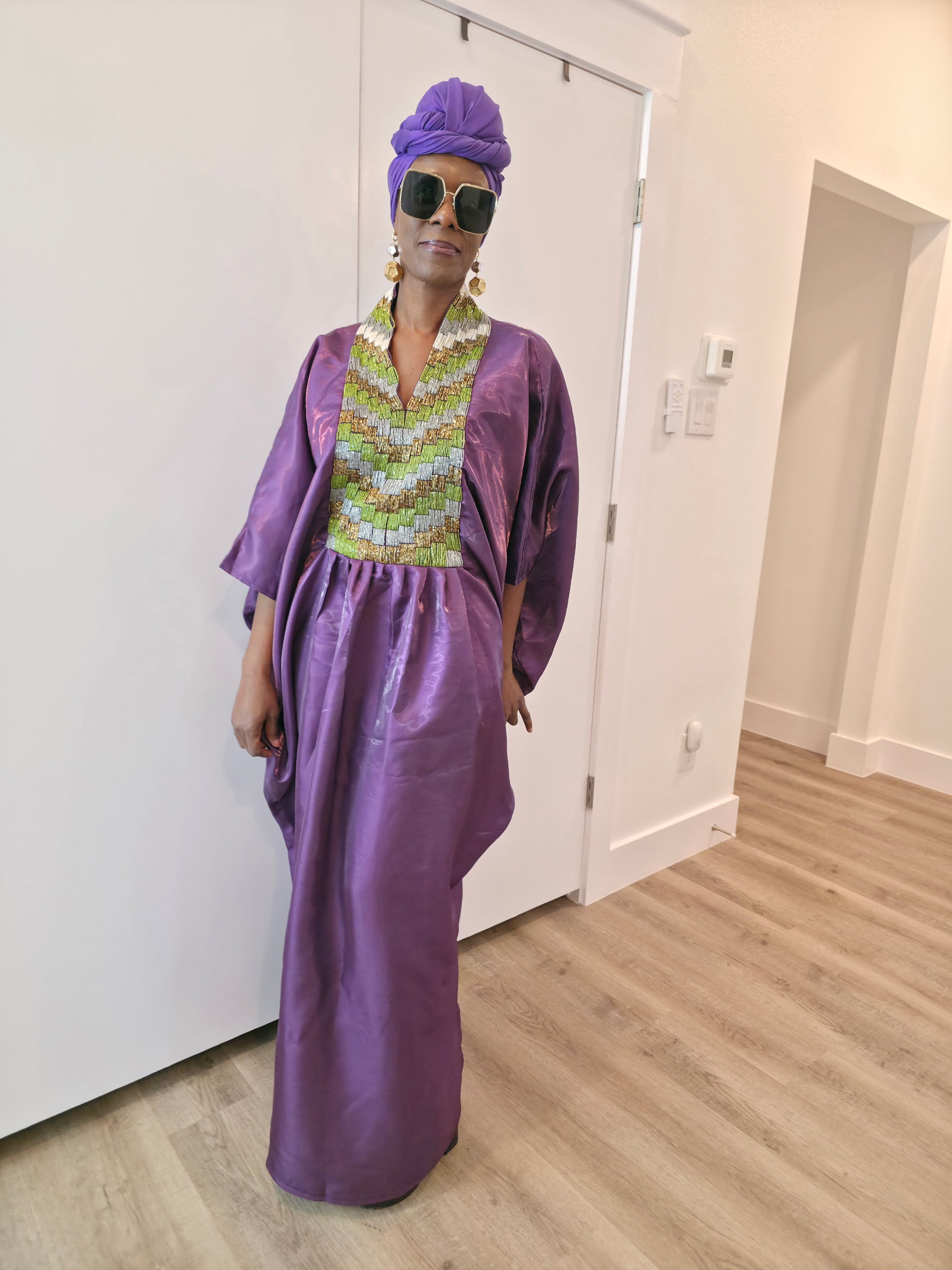 Luxury purple Boubou Kaftan featuring a heavily beaded green and gold bodice, wide sleeves, and a matching purple headwrap.