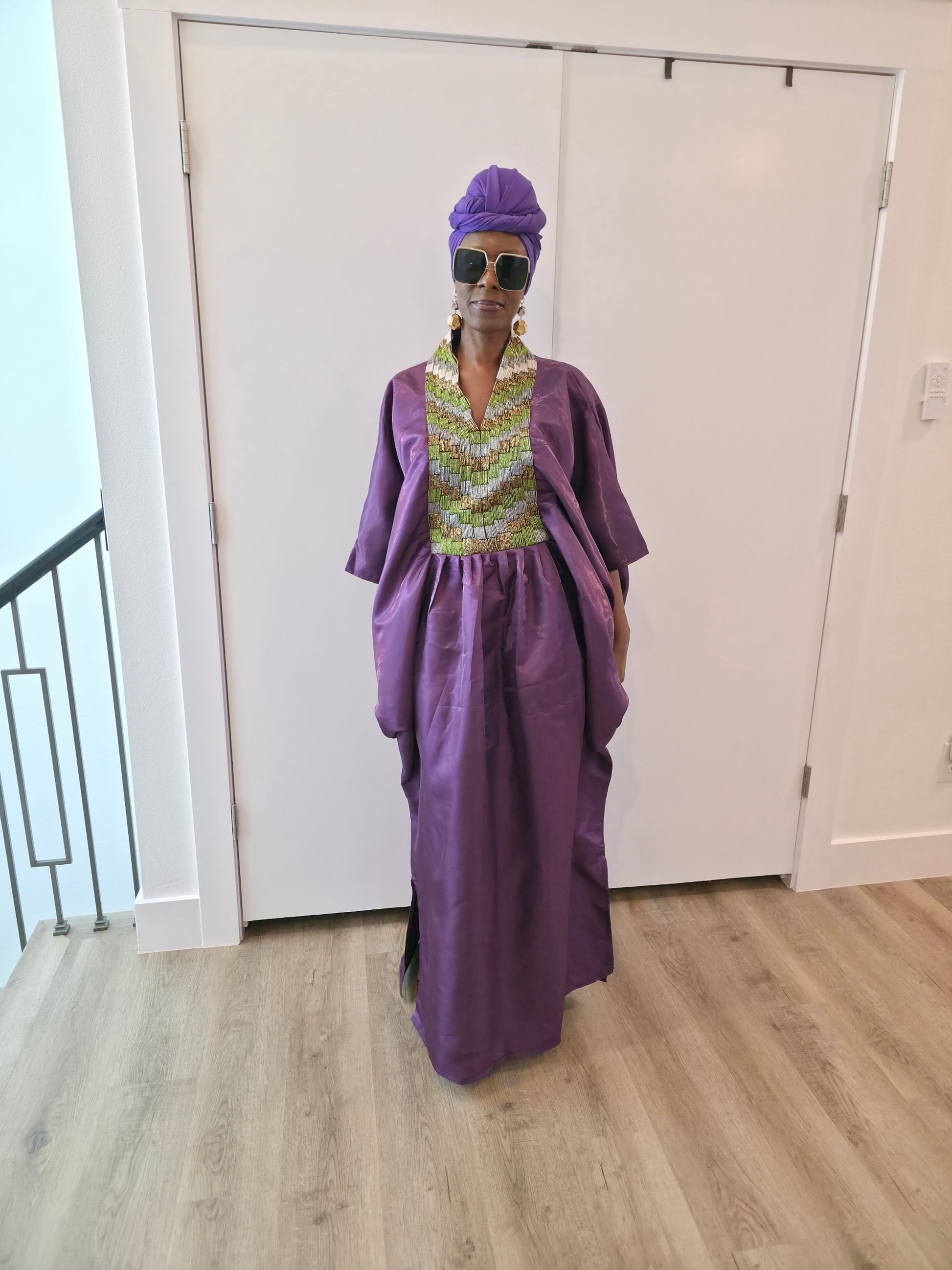 Luxury purple Boubou Kaftan featuring a heavily beaded green and gold bodice, wide sleeves, and a matching purple headwrap.