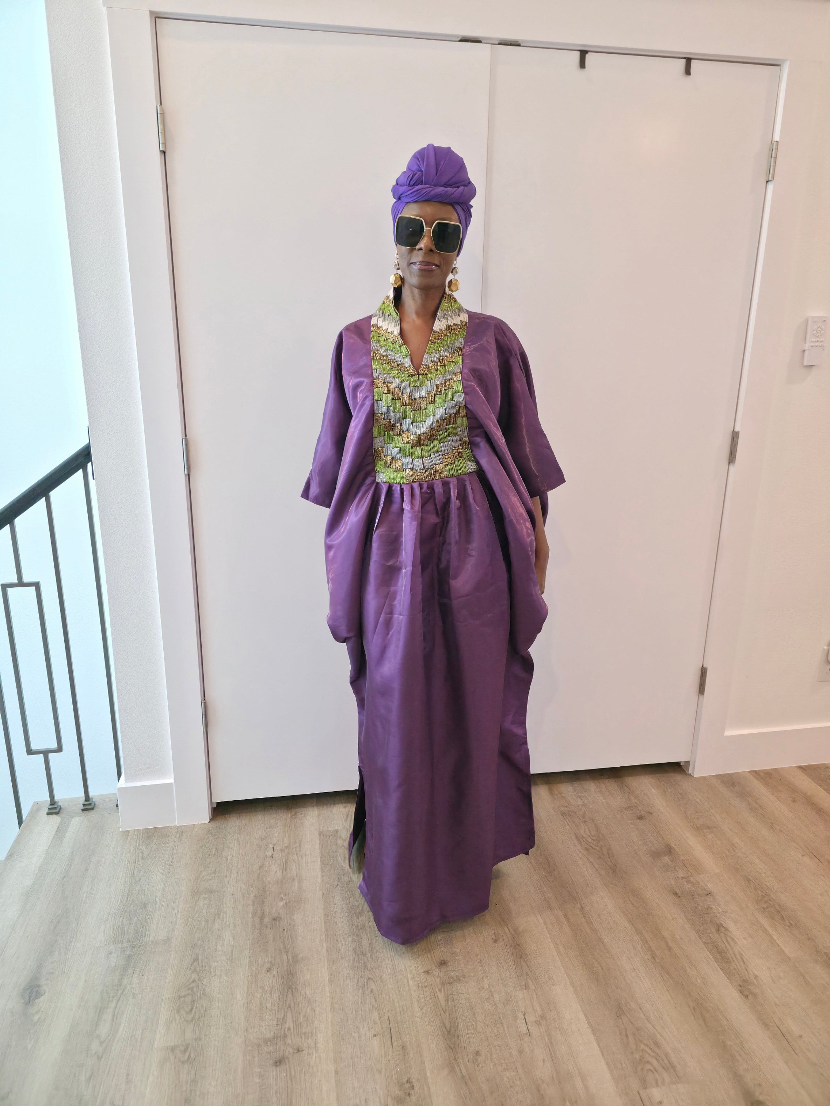 Luxury purple Boubou Kaftan featuring a heavily beaded green and gold bodice, wide sleeves, and a matching purple headwrap.