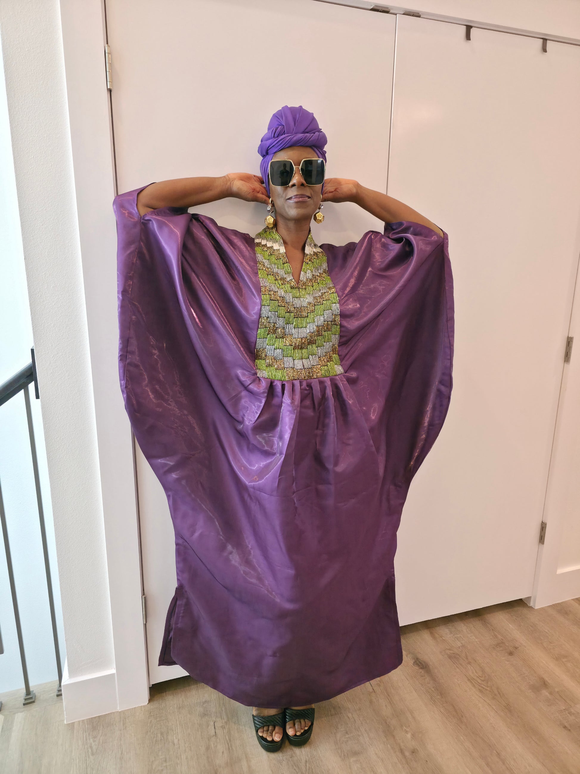Luxury purple Boubou Kaftan featuring a heavily beaded green and gold bodice, wide sleeves, and a matching purple headwrap.