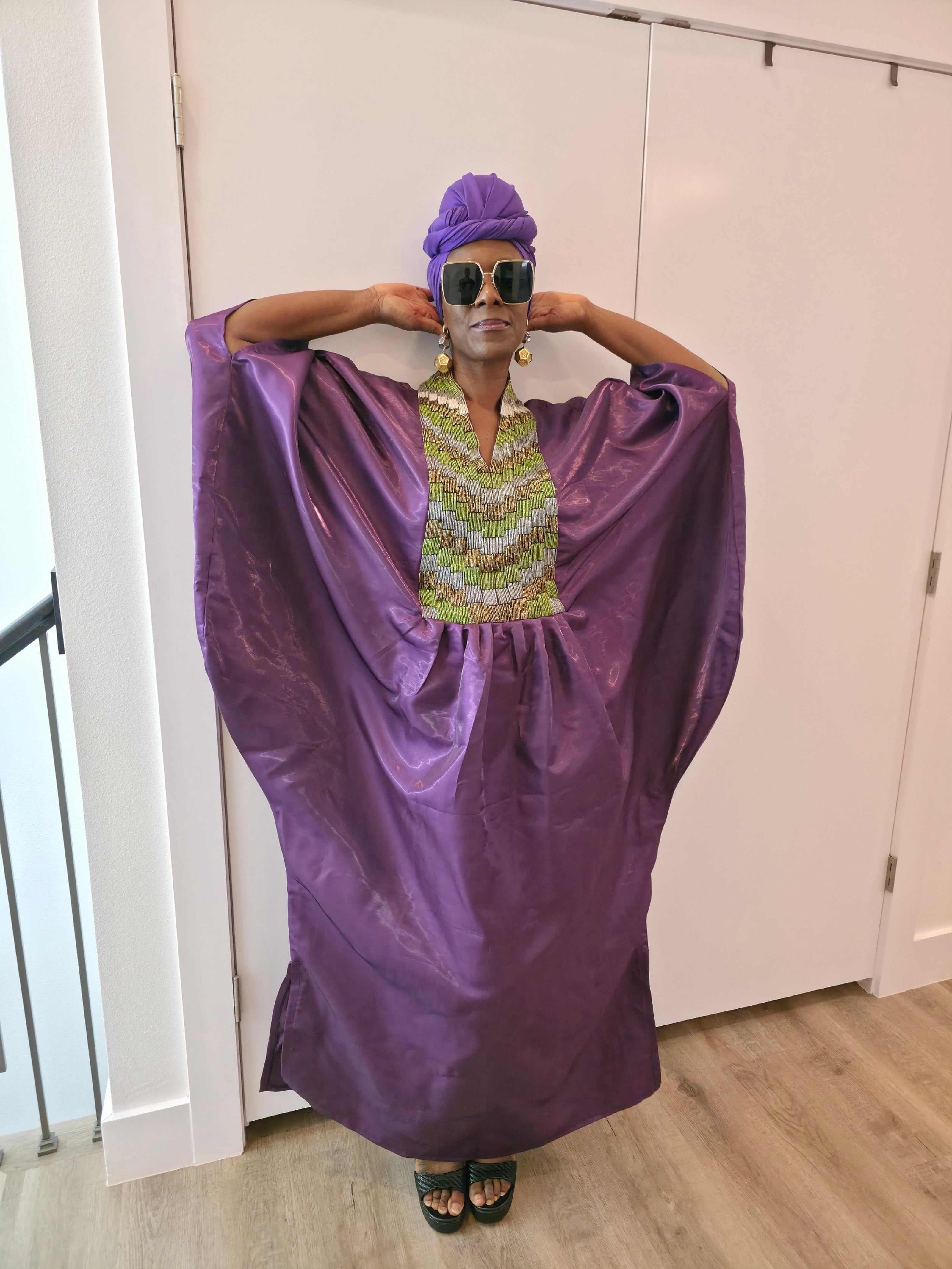 Luxury purple Boubou Kaftan featuring a heavily beaded green and gold bodice, wide sleeves, and a matching purple headwrap.