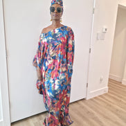 Tropical Dusk Boubou Kaftan featuring an all-over abstract floral print in blue, orange, and pink with a sophisticated off-the-shoulder neckline.