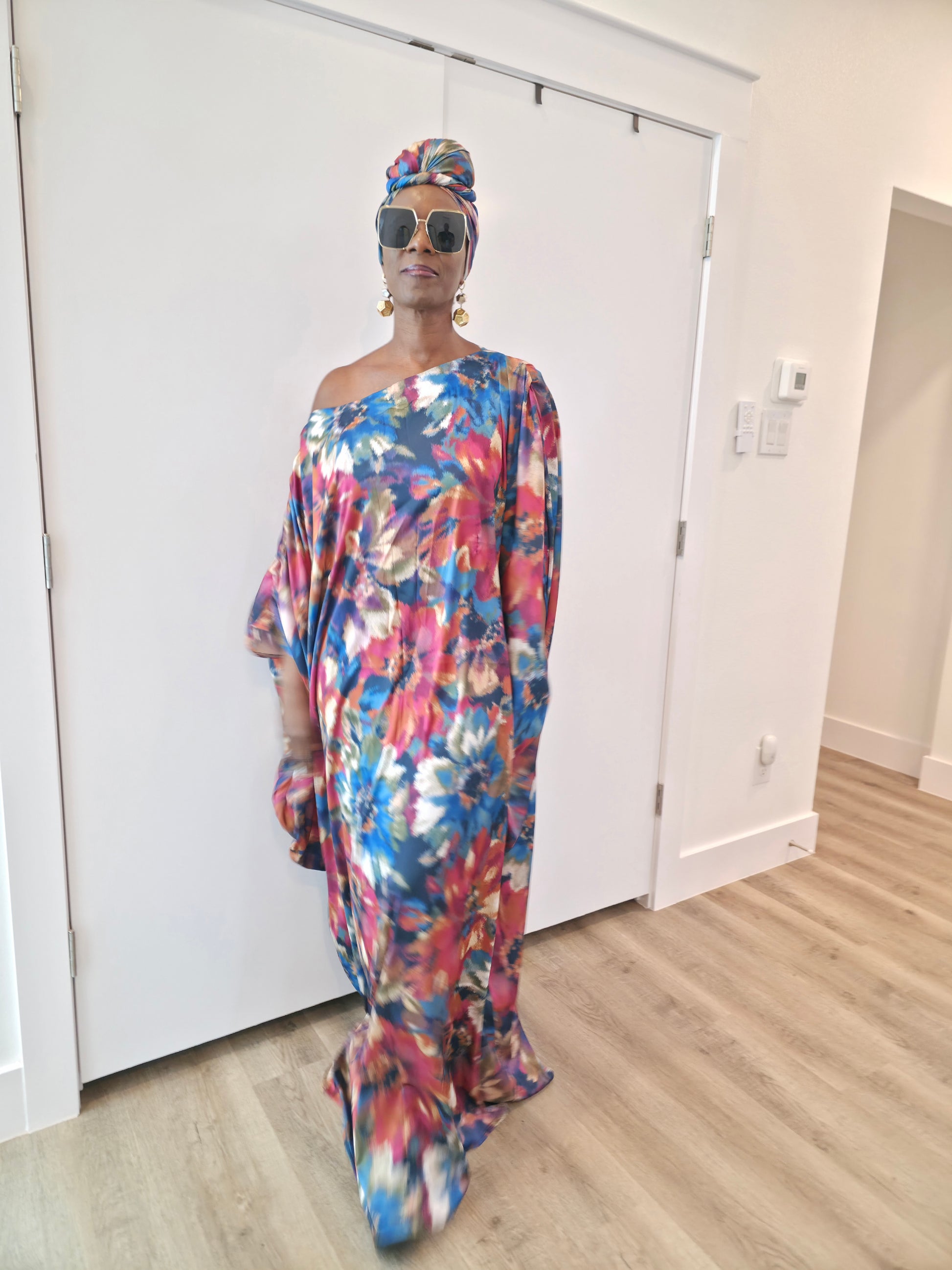 Tropical Dusk Boubou Kaftan featuring an all-over abstract floral print in blue, orange, and pink with a sophisticated off-the-shoulder neckline.