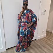 Tropical Dusk Boubou Kaftan featuring an all-over abstract floral print in blue, orange, and pink with a sophisticated off-the-shoulder neckline. 