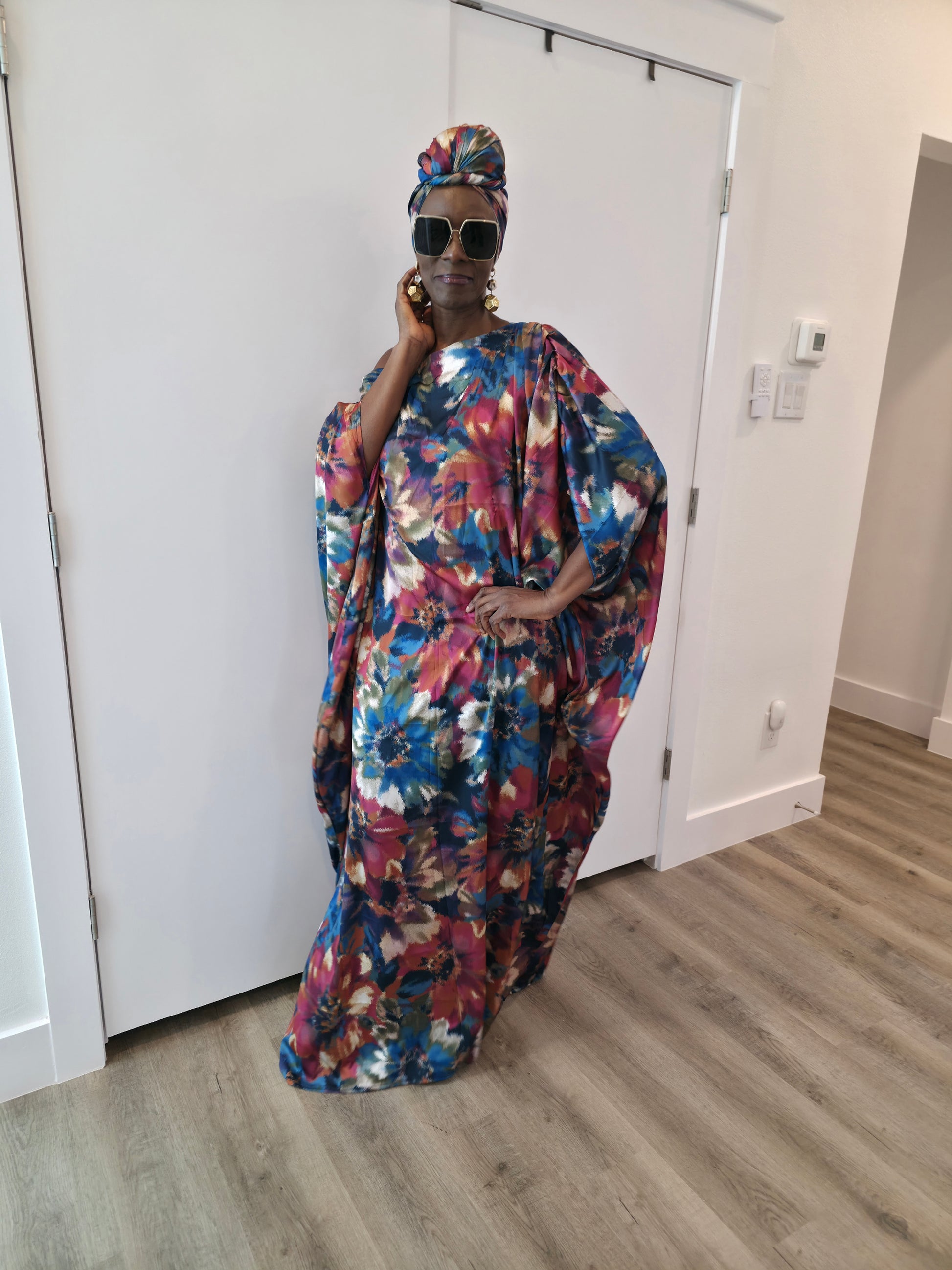 Tropical Dusk Boubou Kaftan featuring an all-over abstract floral print in blue, orange, and pink with a sophisticated off-the-shoulder neckline. 