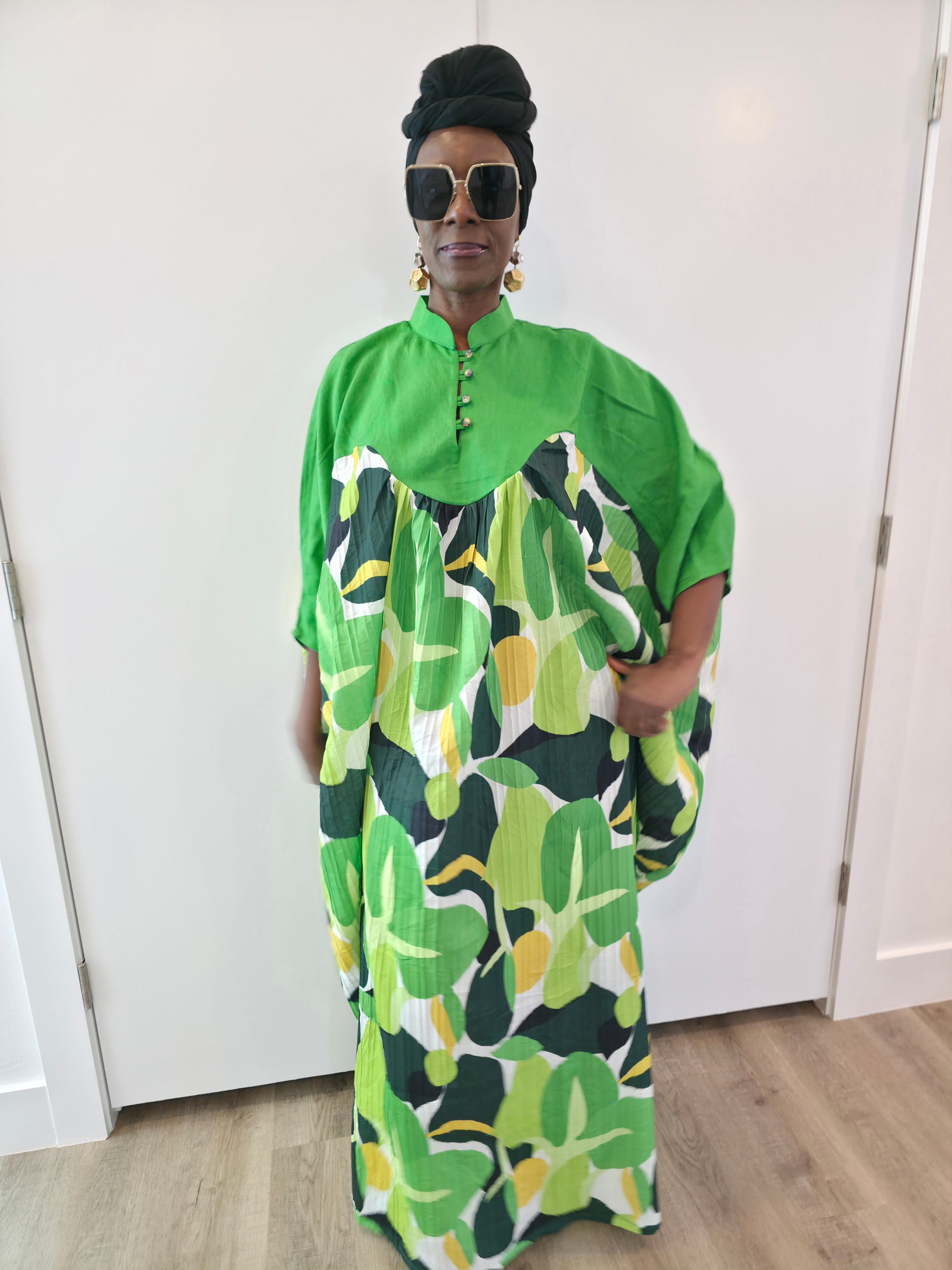 Kaftan featuring a floor-length flowing gown with a structured green bodice and a vibrant, multi-tonal botanical print. Front.