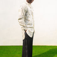 Linen Digital Shirt featuring a cream long-line tunic with black script patterns, a mandarin collar, and side slits paired with black textured wide-leg trousers.