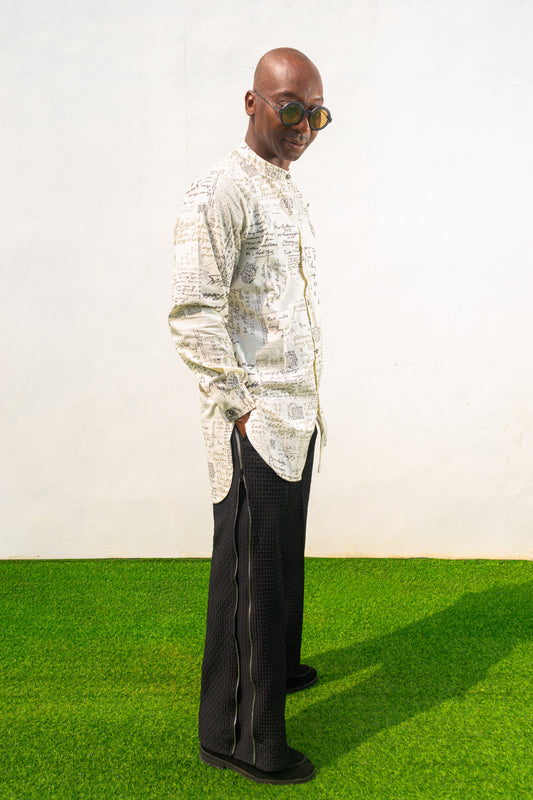 Linen Digital Shirt featuring a cream long-line tunic with black script patterns, a mandarin collar, and side slits paired with black textured wide-leg trousers.