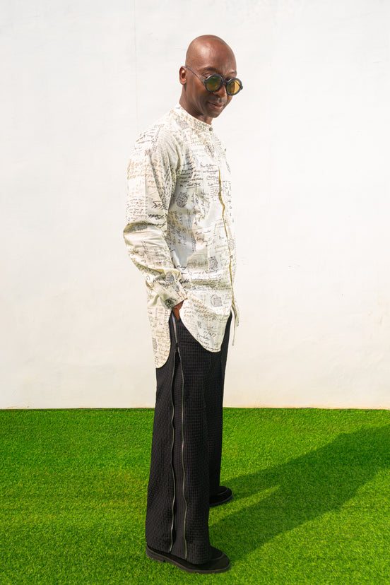 Linen Digital Shirt featuring a cream long-line tunic with black script patterns, a mandarin collar, and side slits paired with black textured wide-leg trousers.