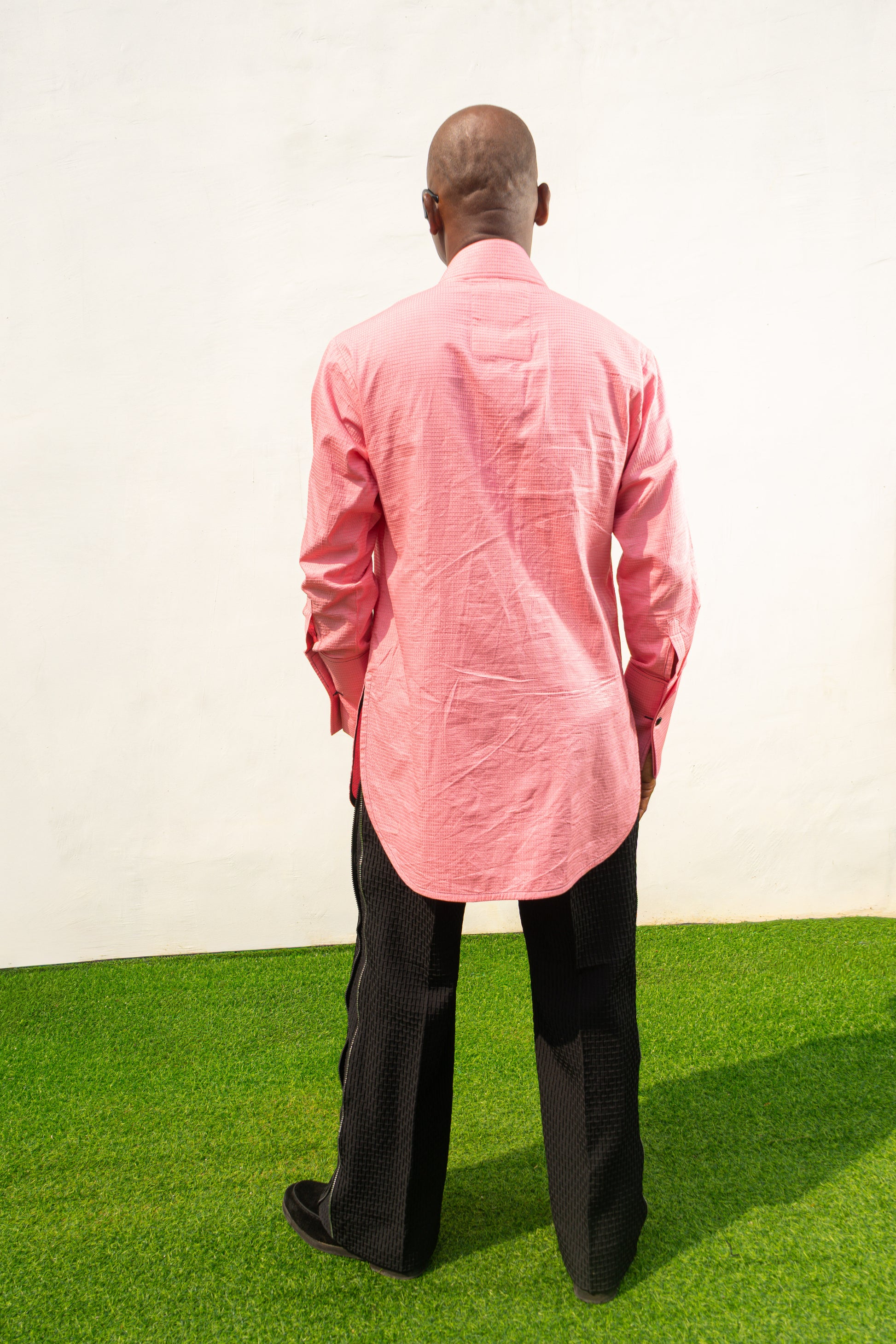 Long Sleeve Shirt featuring a vibrant pink textured fabric, a pleated tuxedo-style chest plate, dark contrast buttons, and a structured mandarin neckline. Back View 