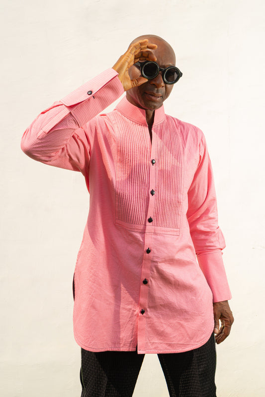 Long Sleeve Shirt featuring a vibrant pink textured fabric, a pleated tuxedo-style chest plate, dark contrast buttons, and a structured mandarin neckline. 