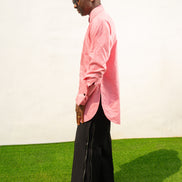 Long Sleeve Shirt featuring a vibrant pink textured fabric, a pleated tuxedo-style chest plate, dark contrast buttons, and a structured mandarin neckline. Side View