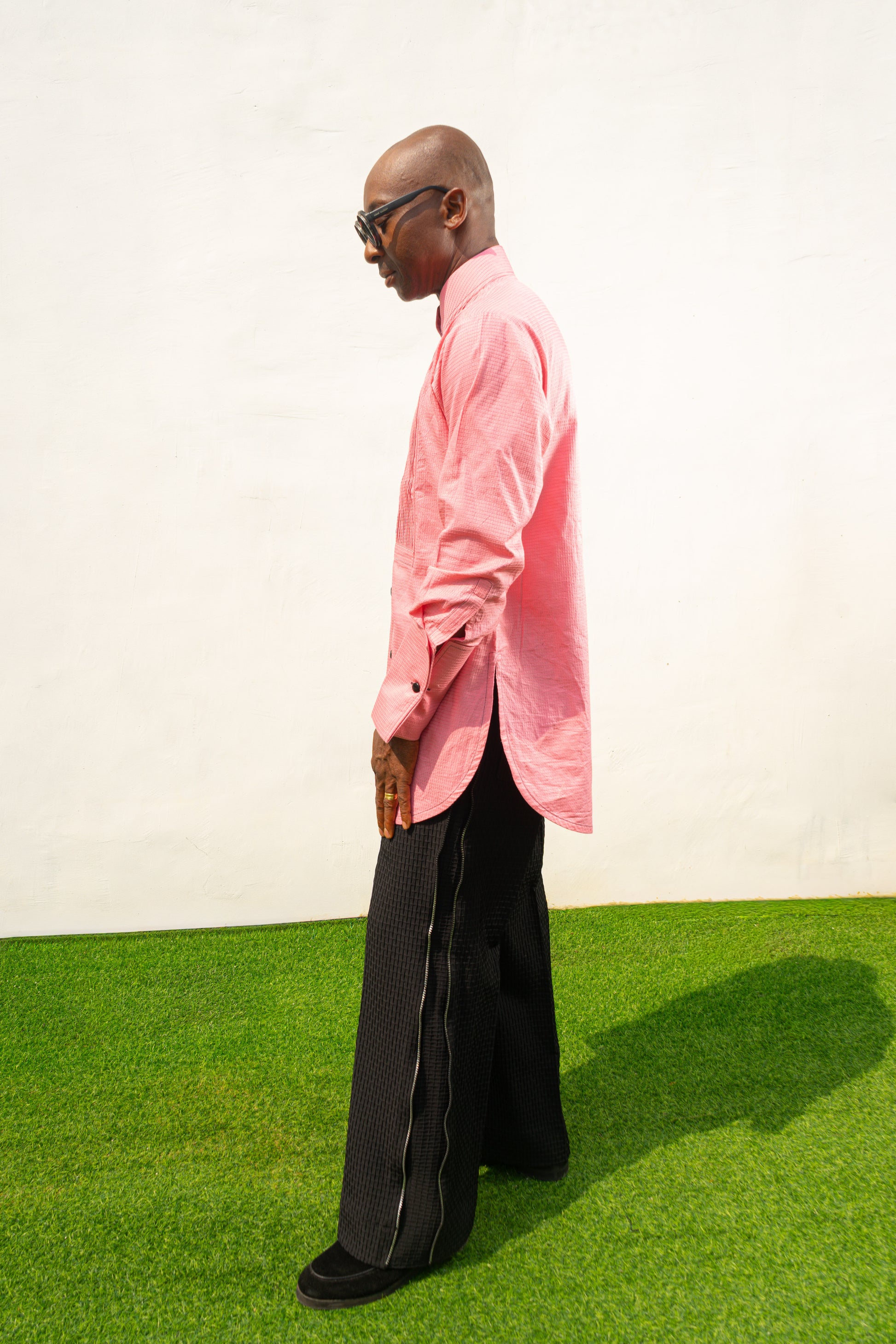 Long Sleeve Shirt featuring a vibrant pink textured fabric, a pleated tuxedo-style chest plate, dark contrast buttons, and a structured mandarin neckline. Side View