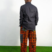 Modern African clothing for men, specifically wide-leg, geometric-patterned Ankara cargo pants in black and orange.