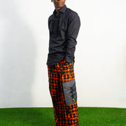 Modern African clothing for men, specifically wide-leg, geometric-patterned Ankara cargo pants in black and orange.
