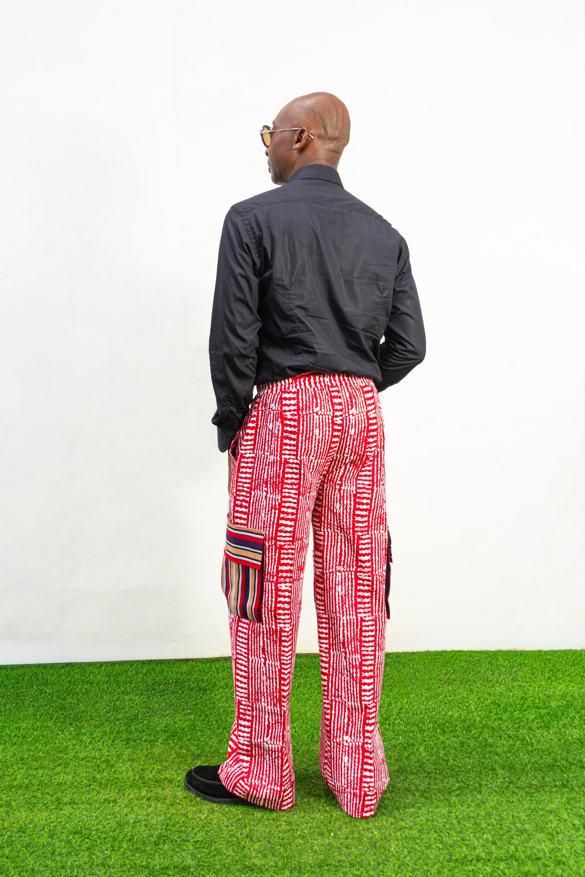 Men's cargo pants featuring a red and white Ankara print, a straight-leg silhouette, and multi-colored striped pocket details.