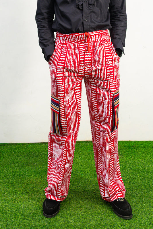 Men's cargo pants featuring a red and white Ankara print, a straight-leg silhouette, and multi-colored striped pocket details.