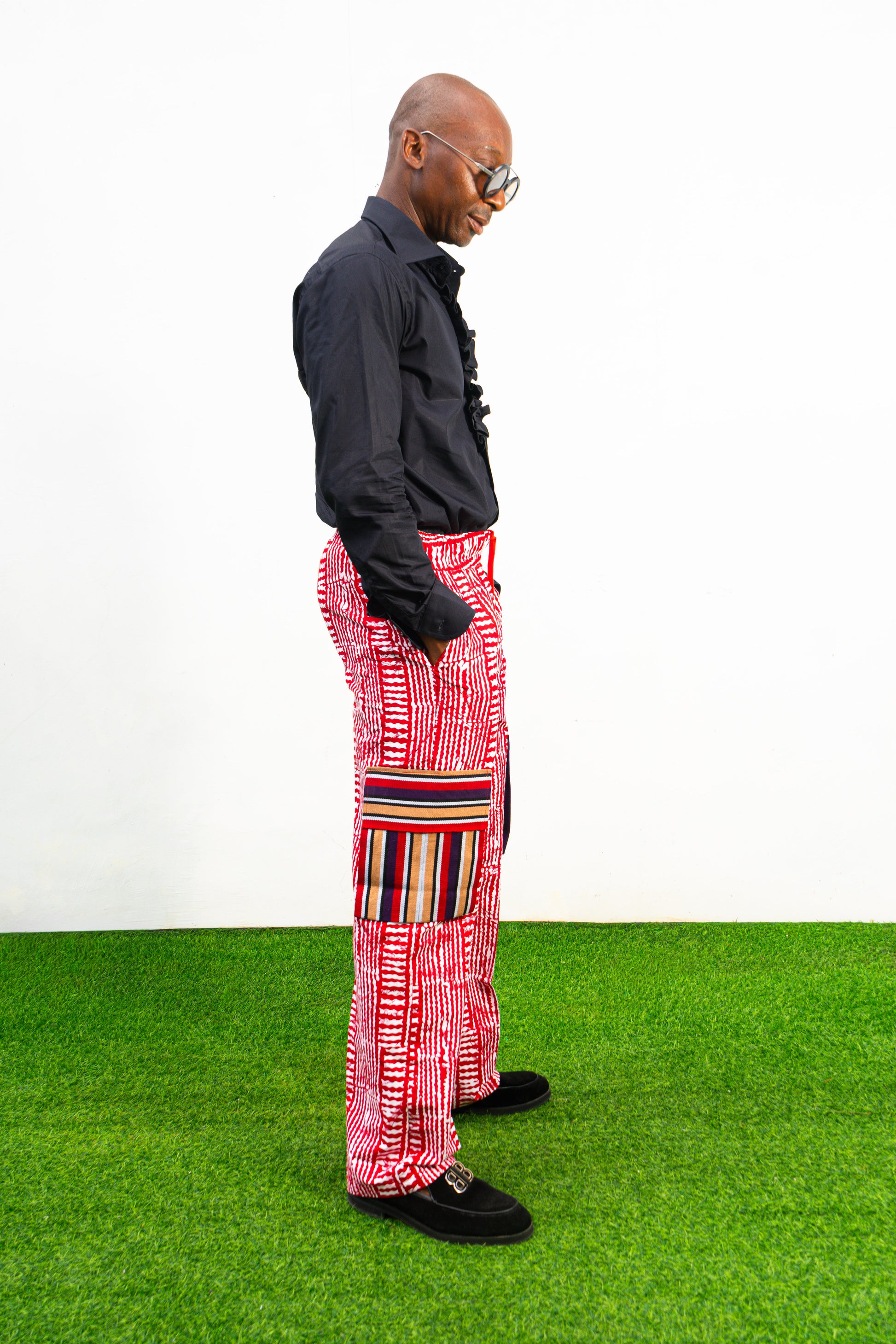 Men's cargo pants featuring a red and white Ankara print, a straight-leg silhouette, and multi-colored striped pocket details.