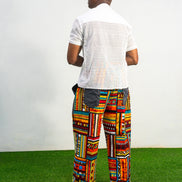 Men's wide-leg pants featuring a vibrant multicolored Ankara patchwork print and oversized grey side pockets.