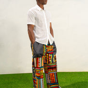 Men's wide-leg pants featuring a vibrant multicolored Ankara patchwork print and oversized grey side pockets.
