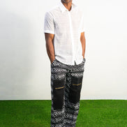 Mens pants featuring a black and white geometric Ankara print with large black front pockets, gold zippers, and a relaxed wide-leg cut.