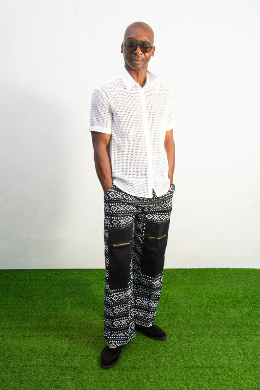 Mens pants featuring a black and white geometric Ankara print with large black front pockets, gold zippers, and a relaxed wide-leg cut.