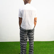 Mens pants featuring a black and white geometric Ankara print with large black front pockets, gold zippers, and a relaxed wide-leg cut.