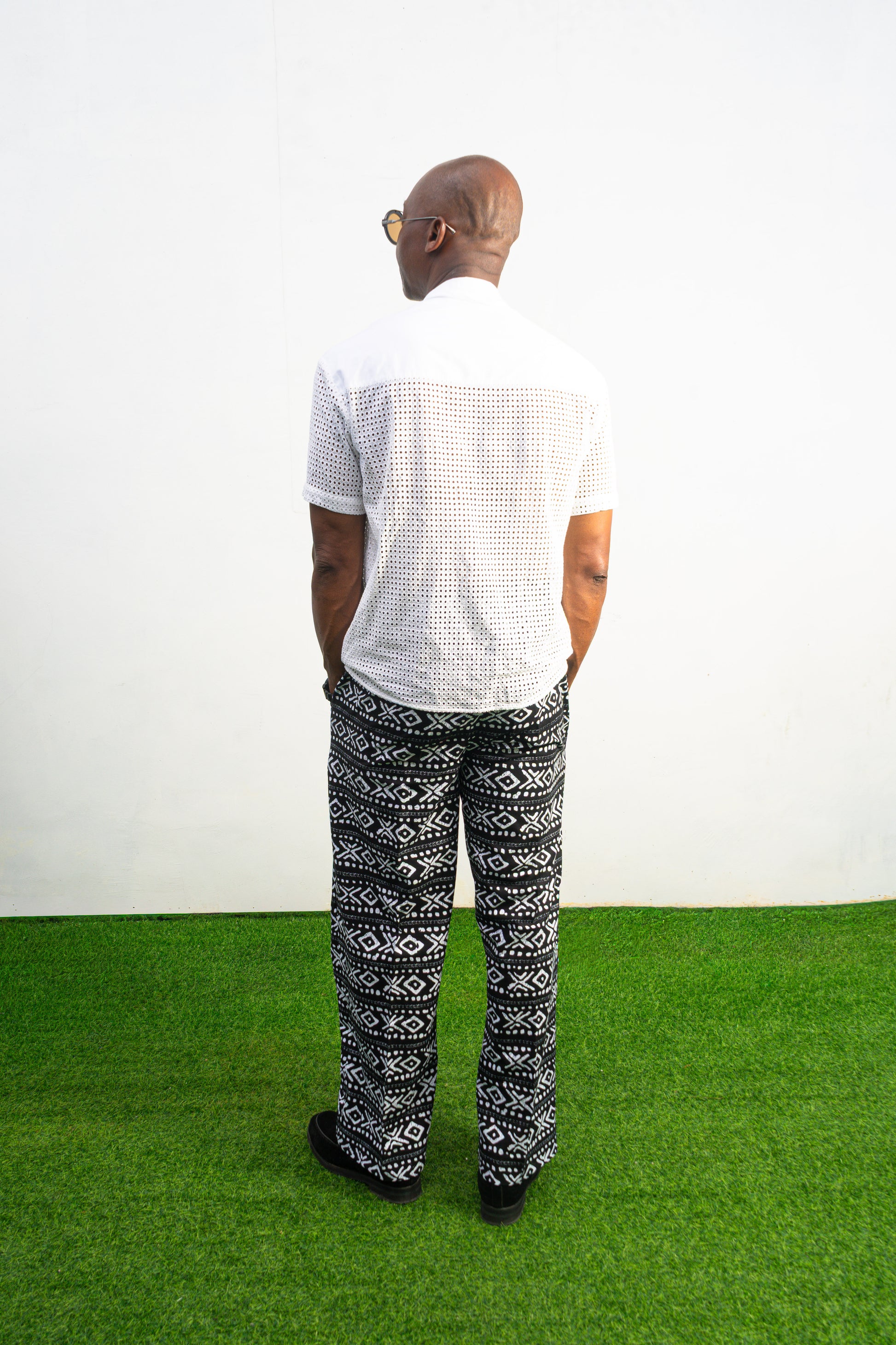 Mens pants featuring a black and white geometric Ankara print with large black front pockets, gold zippers, and a relaxed wide-leg cut.