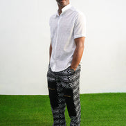 Mens pants featuring a black and white geometric Ankara print with large black front pockets, gold zippers, and a relaxed wide-leg cut.
