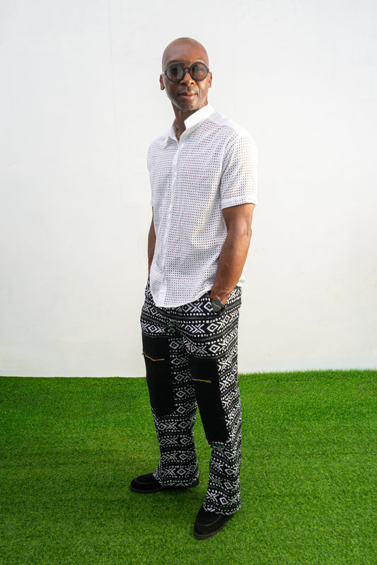 Mens pants featuring a black and white geometric Ankara print with large black front pockets, gold zippers, and a relaxed wide-leg cut.