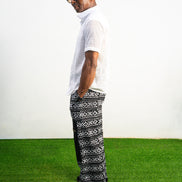Mens pants featuring a black and white geometric Ankara print with large black front pockets, gold zippers, and a relaxed wide-leg cut.