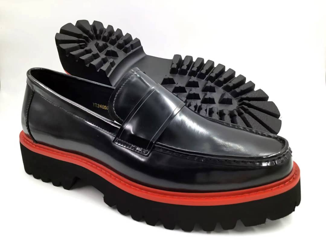 Ruby Track Loafer with its polished black leather penny loafer upper, a vibrant red welt, and a thick black lugged track sole.