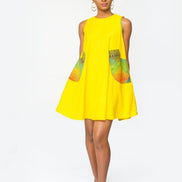 Shift Dress featuring a sleeveless, flowing yellow jersey mini dress accented with colorful geometric African print accents at the shoulders and large curved side patch pockets