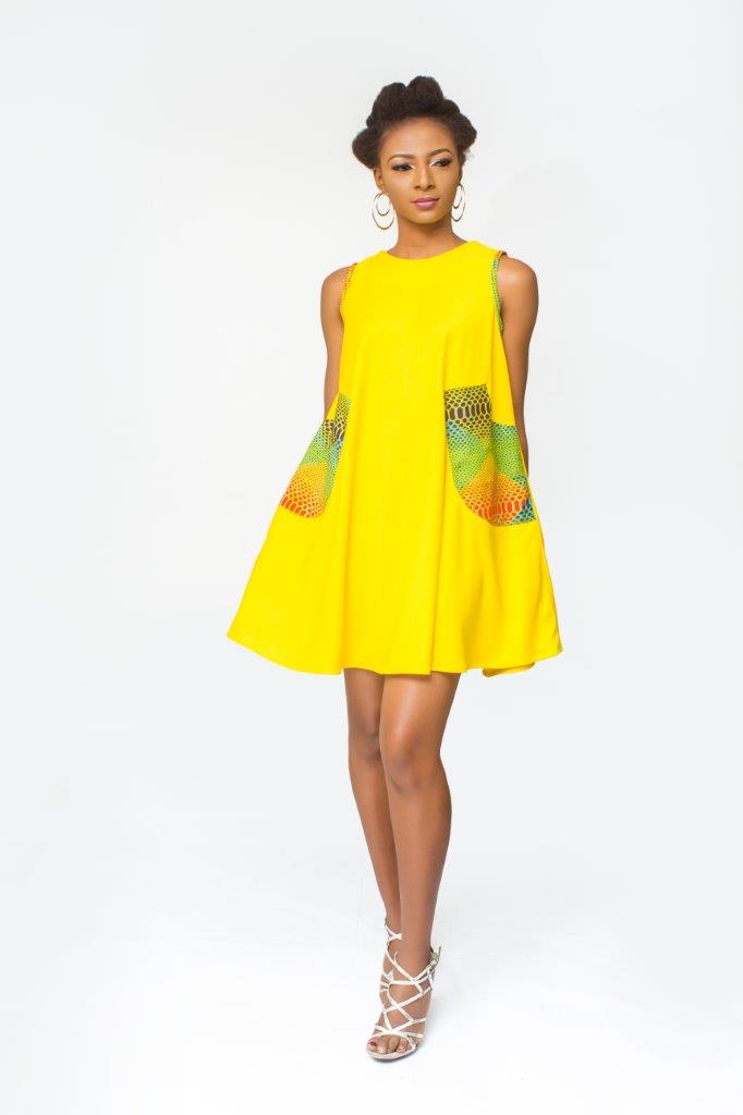 Shift Dress featuring a sleeveless, flowing yellow jersey mini dress accented with colorful geometric African print accents at the shoulders and large curved side patch pockets