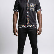 Shirt featuring a short-sleeved black button-down silhouette with vibrant graphic Ankara prints on the collar, pocket, central placket, and hem.