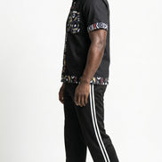 Shirt featuring a short-sleeved black button-down silhouette with vibrant graphic Ankara prints on the collar, pocket, central placket, and hem.