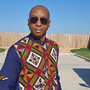 Shirt featuring a vibrant red, yellow, and white geometric Ankara print front panel paired with solid navy blue long sleeves with unique pleated cutouts.