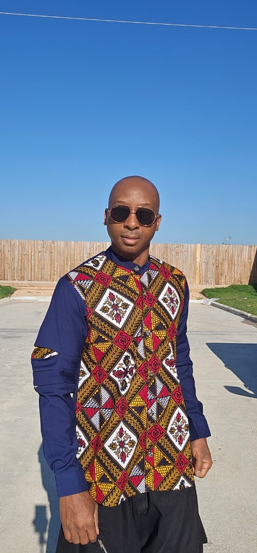 Shirt featuring a vibrant red, yellow, and white geometric Ankara print front panel paired with solid navy blue long sleeves with unique pleated cutouts.