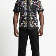 Shirt featuring a short-sleeved button-down silhouette dominated by an abstract, geometric Ankara pattern in white, yellow, and red tones, framed by a solid black collar, pocket, placket, and sleeve bands.