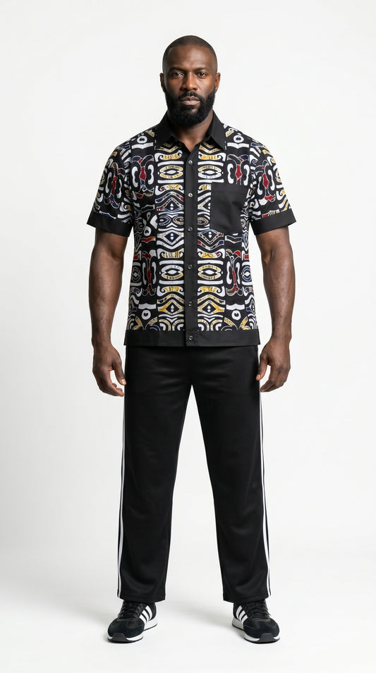 Shirt featuring a short-sleeved button-down silhouette dominated by an abstract, geometric Ankara pattern in white, yellow, and red tones, framed by a solid black collar, pocket, placket, and sleeve bands.
