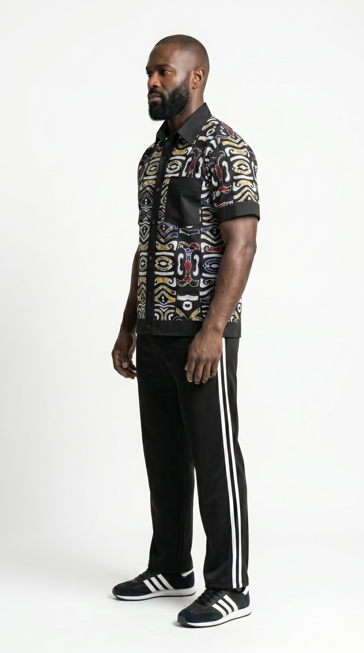 Shirt featuring a short-sleeved button-down silhouette dominated by an abstract, geometric Ankara pattern in white, yellow, and red tones, framed by a solid black collar, pocket, placket, and sleeve bands.