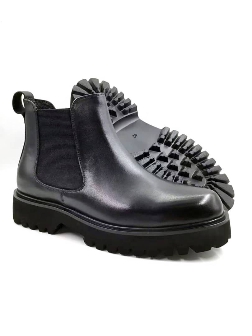 Chelsea Lug Boot with its smooth black leather upper, elastic side panels, and a thick, aggressive black lugged sole.