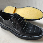 The Croc Derby featuring its black crocodile-embossed leather upper, three-eyelet lacing, and a thick, textured black and gum-colored crepe sole.