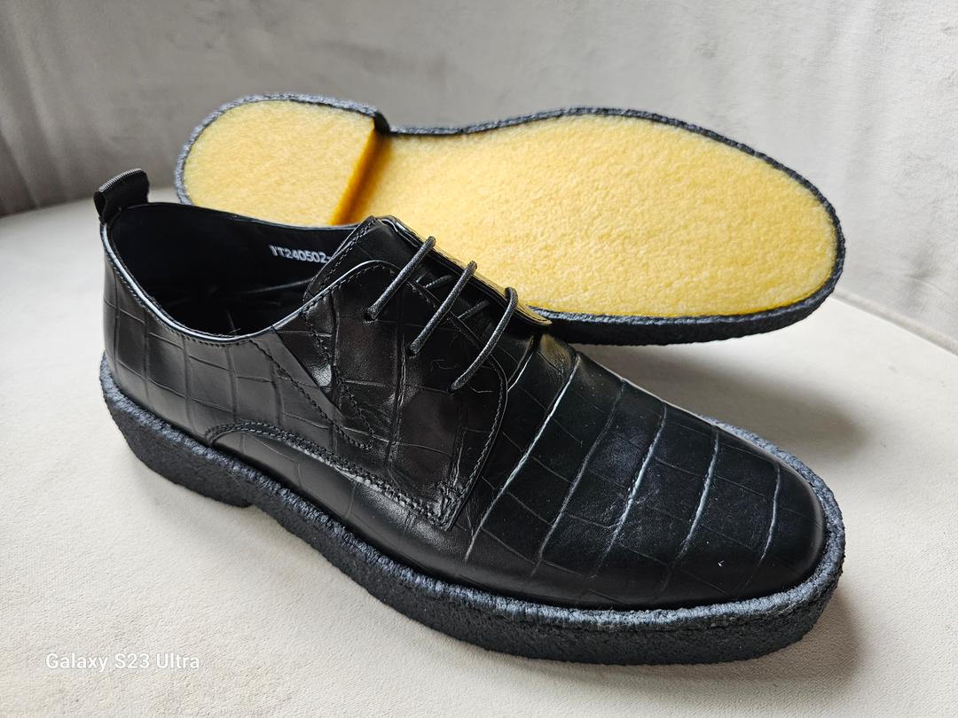 The Croc Derby featuring its black crocodile-embossed leather upper, three-eyelet lacing, and a thick, textured black and gum-colored crepe sole.
