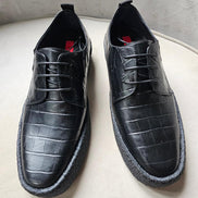 The Croc Derby featuring its black crocodile-embossed leather upper, three-eyelet lacing, and a thick, textured black and gum-colored crepe sole.