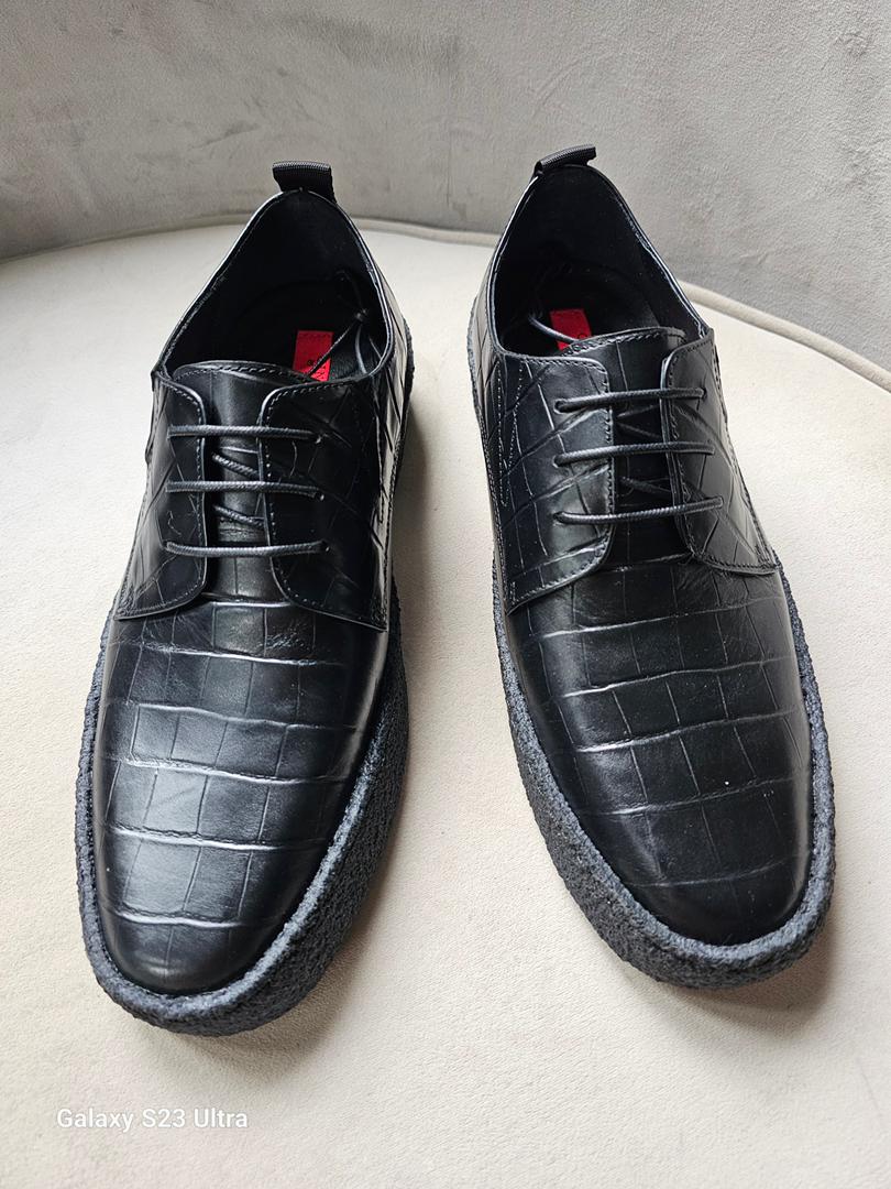 The Croc Derby featuring its black crocodile-embossed leather upper, three-eyelet lacing, and a thick, textured black and gum-colored crepe sole.